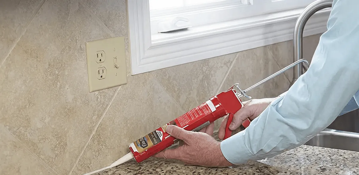 Handyman applying caulk along a kitchen backsplash and countertop seam in Tampa, FL